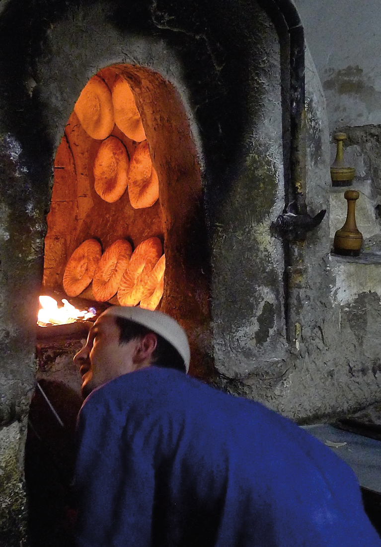 In Bukhara, Erkin nonvoy keeps an eye on loaves baking along the walls of his tandoor oven.