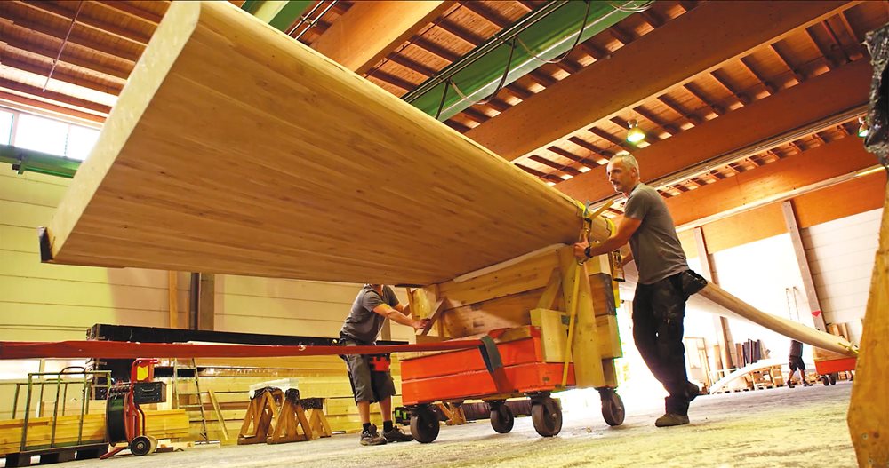 A five-ton composite wooden beam, glued and laminated and bent to twist 90 degrees, gets wheeled into a warehouse in Germany before shipping to Ithra. 