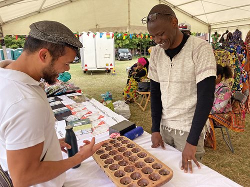 At July’s African Diaspora Festival in Milton Keynes, England, Adam Cheyo, at right, discusses the game with Mujahid Hamidi. Cheyo, 48, grew up in Tanzania, where the advanced version of the game is known as bao la kiswahili (bao of the Swahili people) and bao la kujifunza is literally “bao for beginners.”