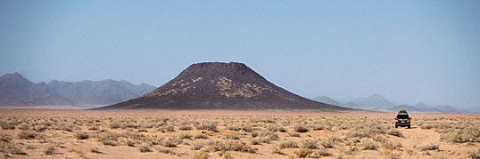 A scoria (cinder) cone in the Hayil region rises from the desert floor.