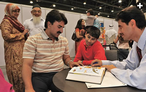 Choosing among vendors from more than 60 countries, a family looks over an encyclopedia. 