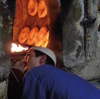 In Bukhara, Erkin nonvoy keeps an eye on loaves baking along the walls of his tandoor oven. 