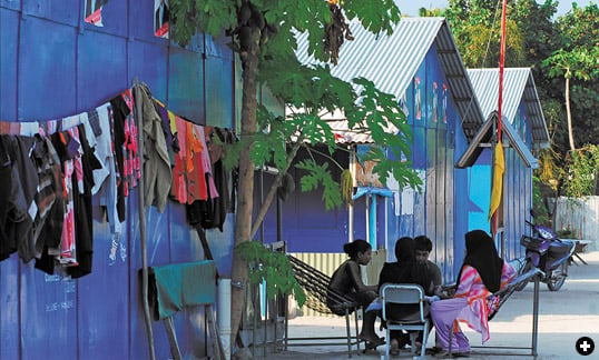 In Meedhoo, refugees from the 2004 tsunami reside in makeshift homes while awaiting completion of permanent homes on Dhuvaafaru, a previously uninhabited island.