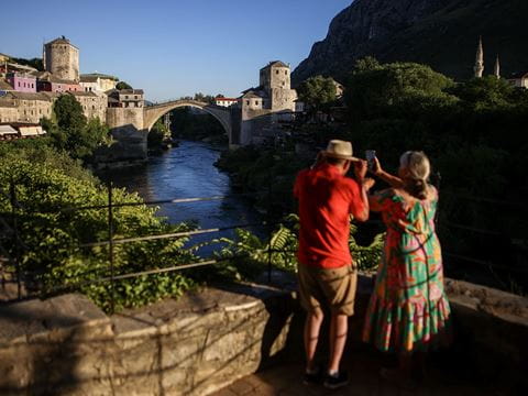 Tourists from the United Kingdom take pictures of the Old Bridge at sunset in Mostar, Bosnia-Herzegovina, this summer. Built in 1566, the Old Bridge was destroyed in the 1992–1995 war, then rebuilt and reopened in 2004.