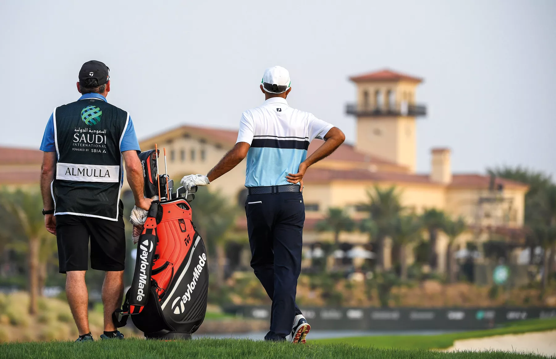 A caddy and Almulla assess the 18th fairway during the first round of the PIF Saudi International in 2019.