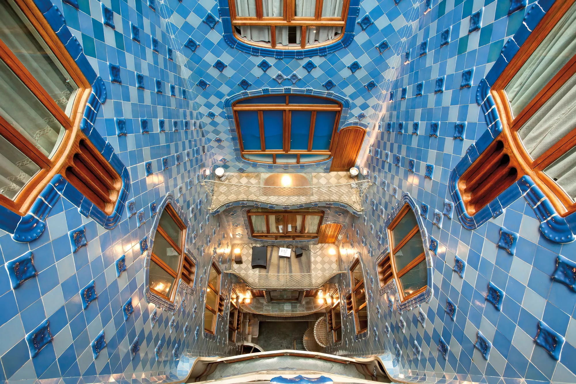 The Patio of Lights at Casa Batlló uses glazed tiles, graduated color and a central courtyard to control natural light. The design shows how Gaudí adapted principles associated with Andalusi and Islamic architecture rather than simply copying their forms.
