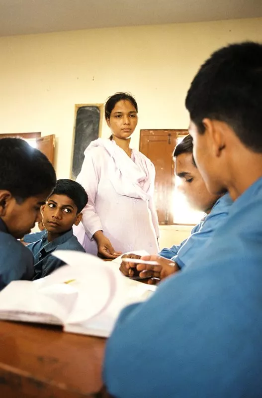 A teacher checks the class work of boys at the Edhi Child Home. Requirements that older students help younger ones help integrate Edhi's philosophy of self-reliance into the curriculum.&nbsp;
