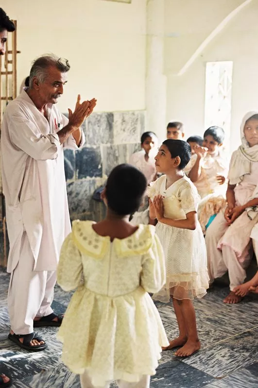 Anwer Kazmi, Edhi's right-hand man, warmly encourages a song and dance that a child offers him during rounds of the mental patients' wards at Edhi Village.&nbsp;