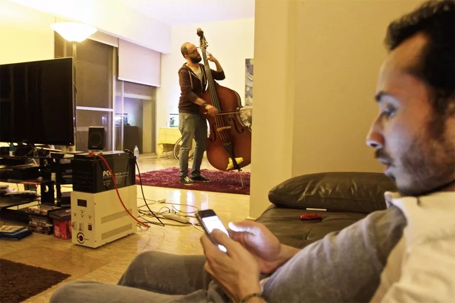 <p>Tanjaret Daghet's guitarist Khuluki relaxes while Omran practices in the apartment shared by the trio-in-exile: &nbsp;Each band member left a family and friends in Syria. They are now at work on their second album of ferocious guitar, raucous drums and vocals that veer eclectically between boisterous rock-n-roll and soulful <em>mawwal</em>-type chanting.</p>
