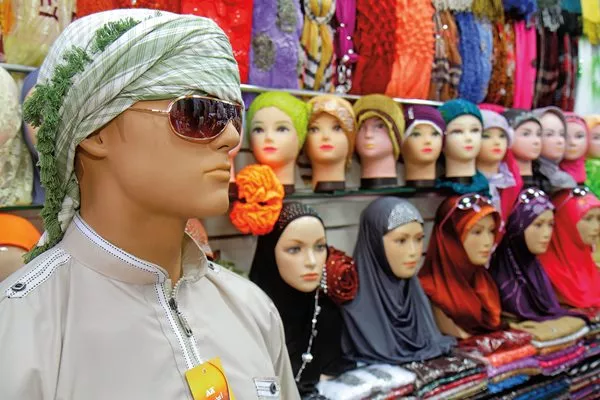 In Dubai’s Deira Murshid Bazaar, a mannequin displays a printed kufiya, wrapped turban style, in front of scarves and hijabs for women. <i>Below</i>: An Instagram post by Danish fashion label Cecilie Copenhagen, whose founder, Cecilie Jørgensen, creates dresses, tops, shorts, belts and jackets all inspired by kufiyas.
