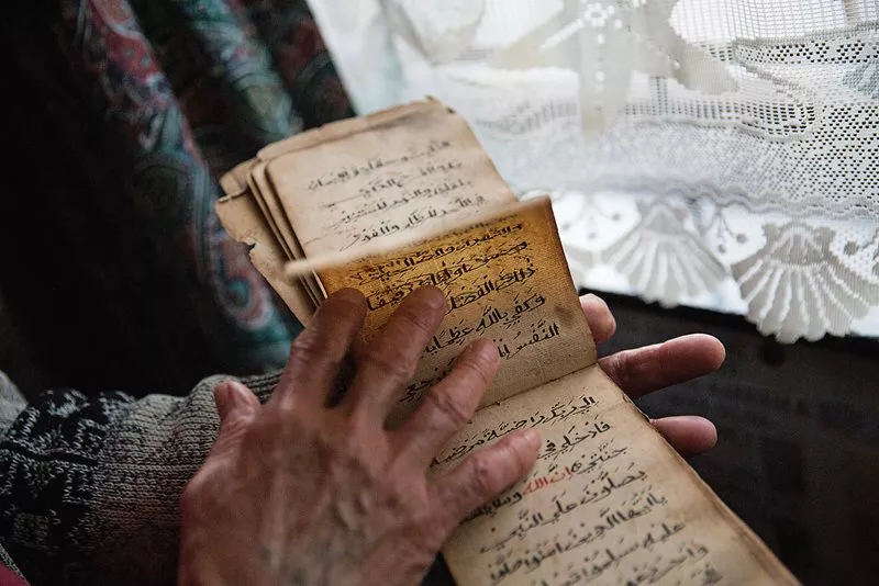 Ebraheim holds one of many kitabs he has collected from self-taught families over the years, which he donates to the Simon's Town Heritage Museum.