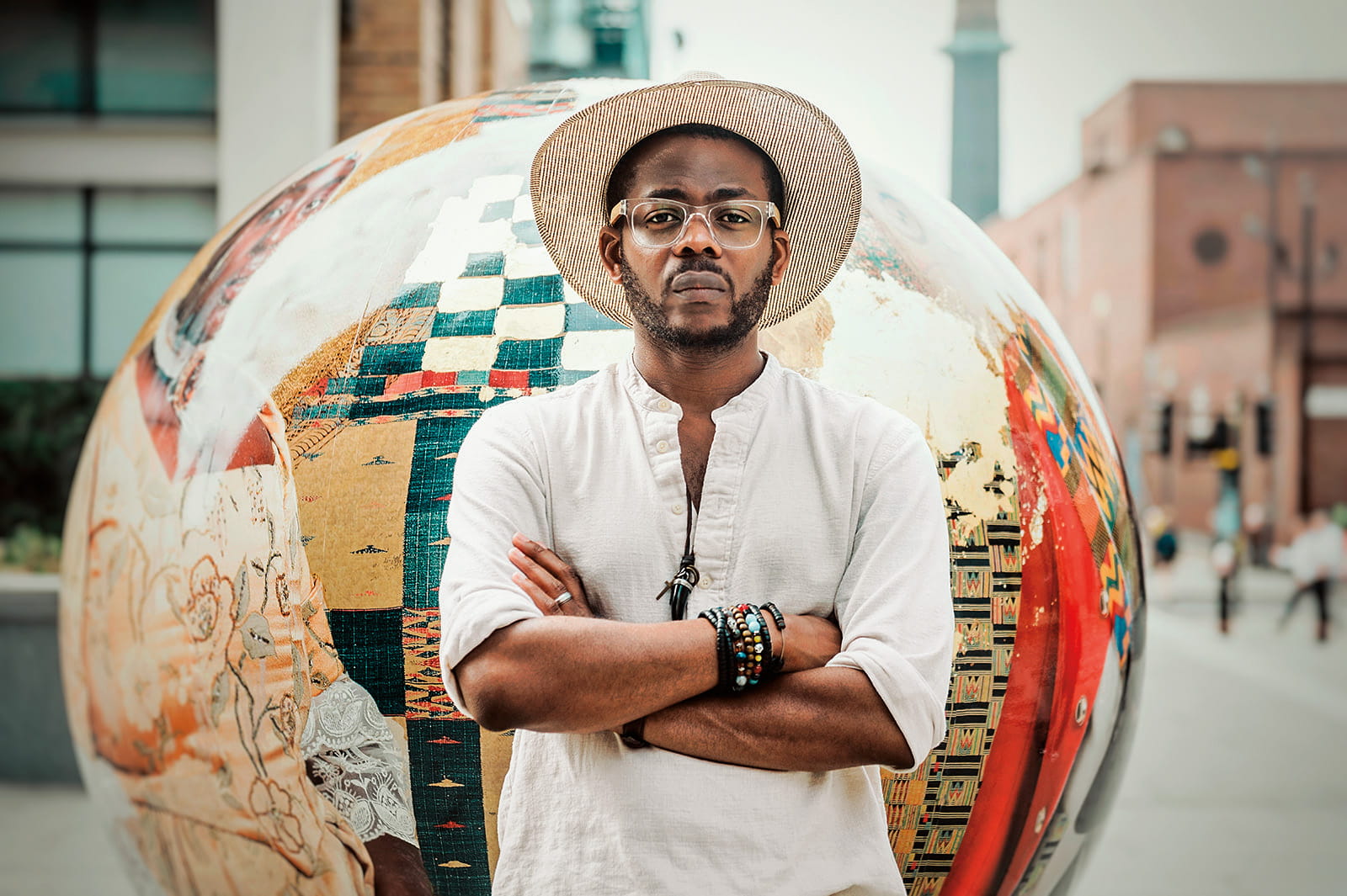 artist Àsìkò standing in front of globe-shaped art piece