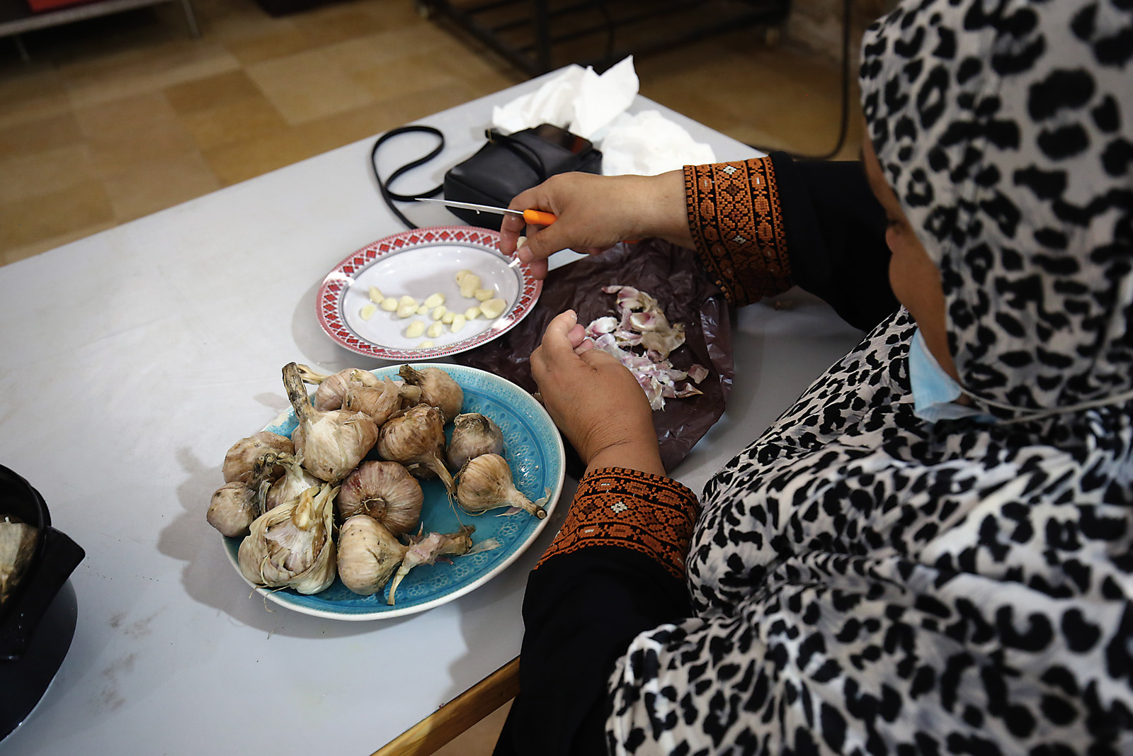 Five Centuries of Jerusalem Soup - Nozwa Kark, whose hands appear peeling garlic, helps prepare the day's soup.