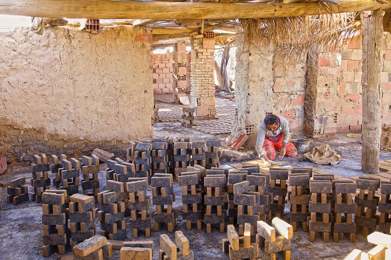 Surrounded by stacks of drying bricks, eighth-generation Tozeur brickmaker Antar Chorba pushes a wet mix of clay into block form as many as 600 times in a day. The bricks dry in stacks that will later be fired.
