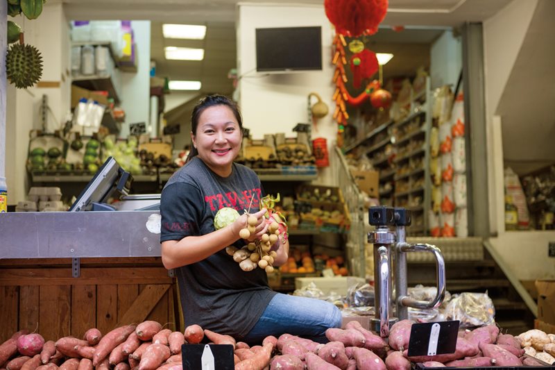 Along the busy Rue Halle Delacroix, Bêline Sy poses at her family’s store,  Tam-Ky, which the Sys started after emigrating in 1979 from Vietnam, when she was a baby. Today the shop sells everything from produce to dried seaweed to prepared Vietnamese dishes.