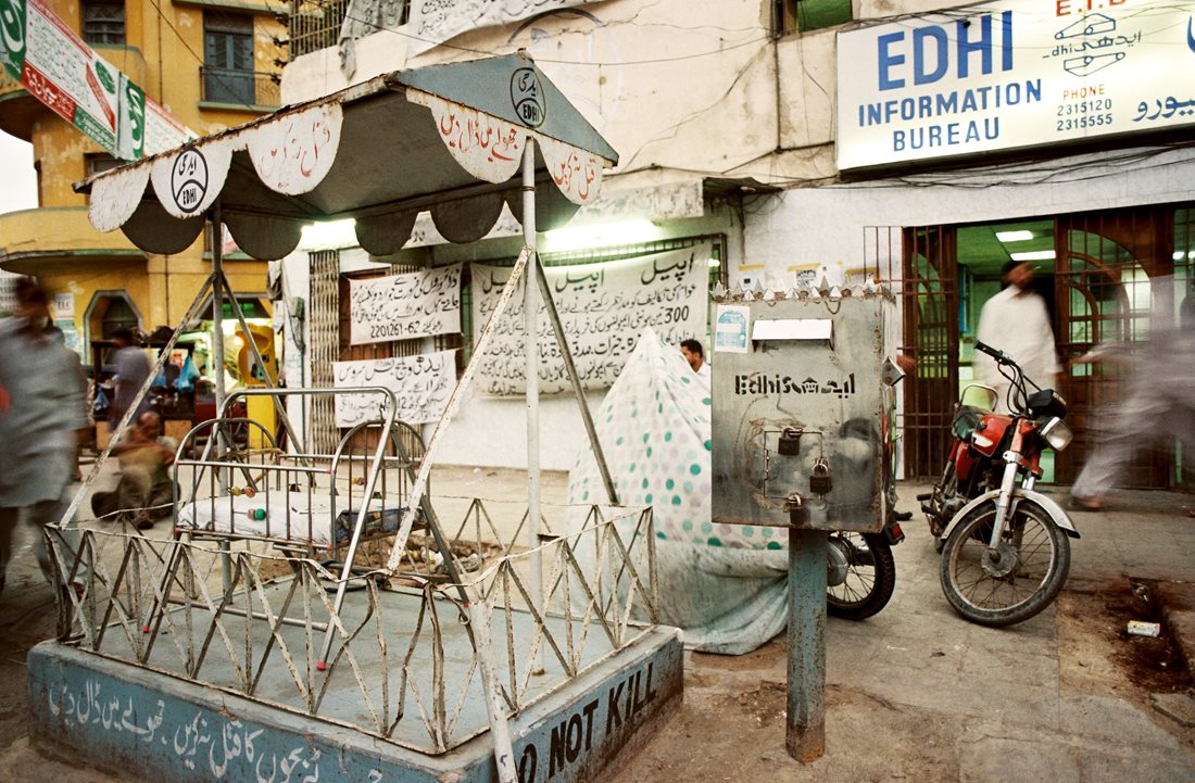 The Edhi Information Bureau is one of several Edhi centers in Karachi is one of some 300 throughout Pakistan. From here the Edhi ambulance service is coordinated, and there is a free kitchen, a missing-&shy;persons bureau and a collection center for donations of cash and bed&shy;ding. Like all Edhi centers. it has outside its door a shaded cradle near&nbsp;which is a sign that reads, &ldquo;Do not kill.&quot;