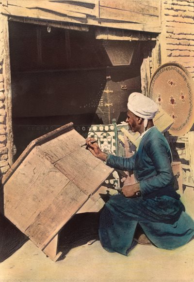 <p>Shown working near the Euphrates River in Iraq in 1922 in this hand-colored photo, a craftsman is decorating a wooden chest. Although demand today is greatly diminished, the tradition of making chests continues, from ornate, handcrafted chests to mass-produced metal boxes.</p>
