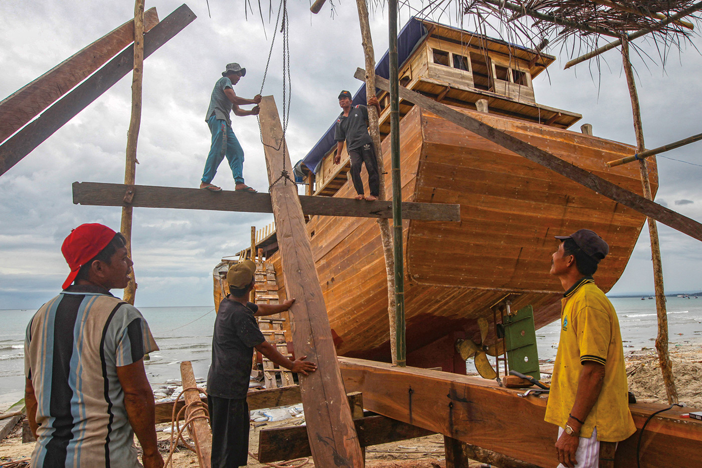 Shipbuilders construct a traditional Pinisi boat in Tana Beru, on Indonesia's South Sulawesi island. - The iconic schooners, known as Pinisi, have given the builders a reputation as master craftsmen and some of the best sailors in the world.