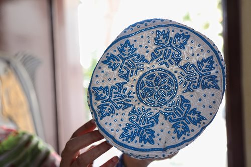 Natural light from a window brings out the detail of a blue-on-white kummah.