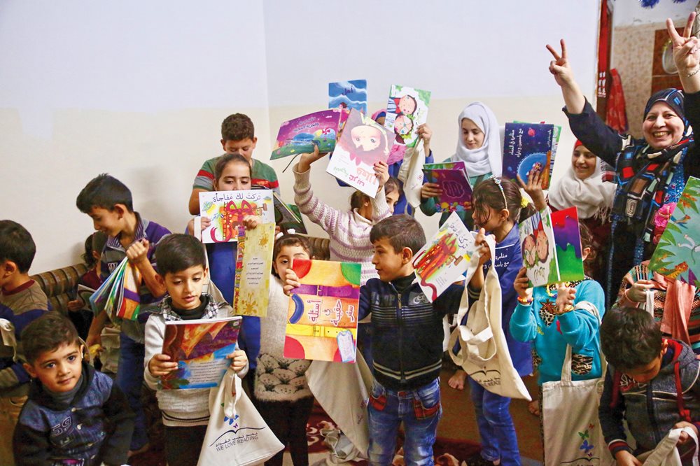 Children receive books after a read-aloud session in Ajloun, Jordan. To date WLR has worked with authors and illustrators to publish 32 children’s books, and it has given away more than a quarter million books.