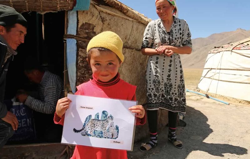 In Tajikistan&rsquo;s Akhtam Valley, a child holds up an illustration of a snow leopard that was part of an educational effort to assist residents living in shared habitat to protect both the species and their own livelihoods.