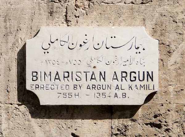 <p>This plaque on the wall of the Bimaristan Arghun in Aleppo, Syria, commemorates its founding by Emir Arghun al-Kamili in the mid-14th century. Care for mental illnesses here included abundant light, fresh air, running water and music.&nbsp;</p>
