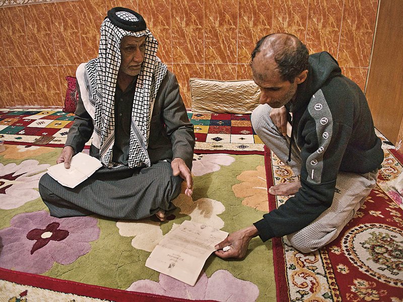 Bin Thuqub’s son Hadi lives nearby. Here he looks at his father’s now-worthless deed to the land Bin Thuqub once farmed and grazed buffalo in Rufaiya, the village in the marshes where Bin Thuqub had grown up. 