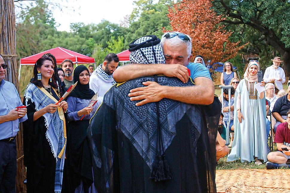 Mohanned Neamah, front, and Azzam Alwash embrace. After so much work in both Iraq and in the US, emotions run high at the opening of the mudhif. “Be proud that this represents you, that you came from the reeds,” said Alwash. “Yes, we went out in the diaspora, but this mudhif brought us back together.” 
