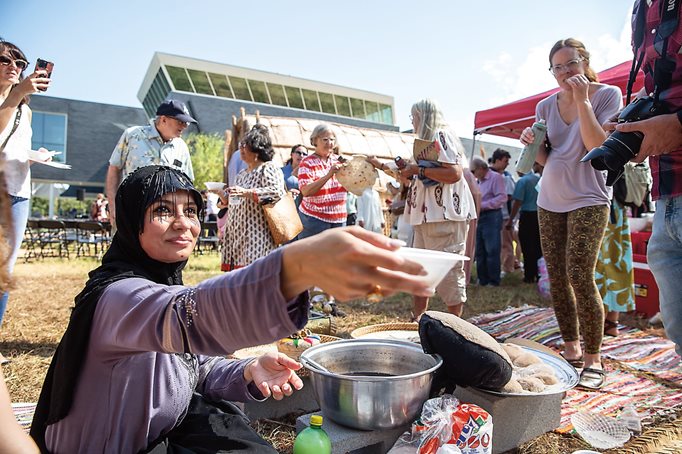 Israa Mahdi serves dates to guests at the opening. The Baghdad native helped build the mudhif. 