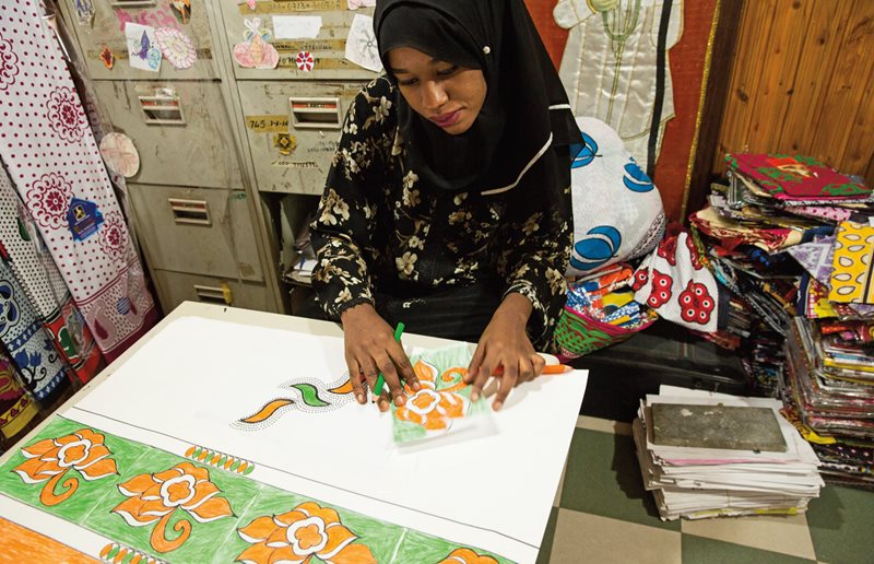 Chavda designer Sabrina Ally, 24, has designed many of Zanzibar&rsquo;s boldest and most popular kanga. Surrounded by piles of kanga fabric, she draws and stencils new patterns.