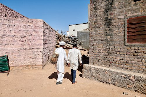Lakha Khan is carrying a drum to his home, accompanied by his grandson.