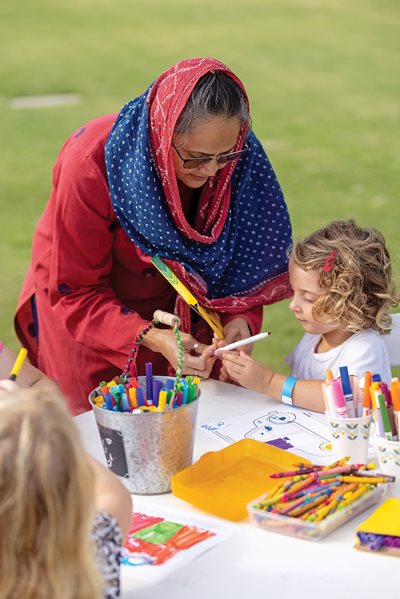 Khan guides a young participant at Art 120’s Jingle Trucks Family Fun Day on the Riverfront in August in Chattanooga, one of the program’s several public events intended to help children appreciate how art from different perspectives cultivate common understandings.