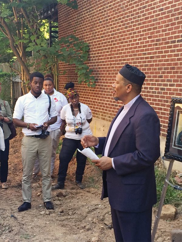 <p>Taib Shareef, imam at Masjid Muhammad in Washington, D.C., offers <em>salat al-janazah&mdash;</em>the traditional Muslim funeral prayer&mdash;for Yarrow Mamout on the site of his former home at Dent Place. Mamout was said to have been buried in the corner of the garden where he &quot;resorted to pray&rdquo; at the time of his death in 1823.</p>
