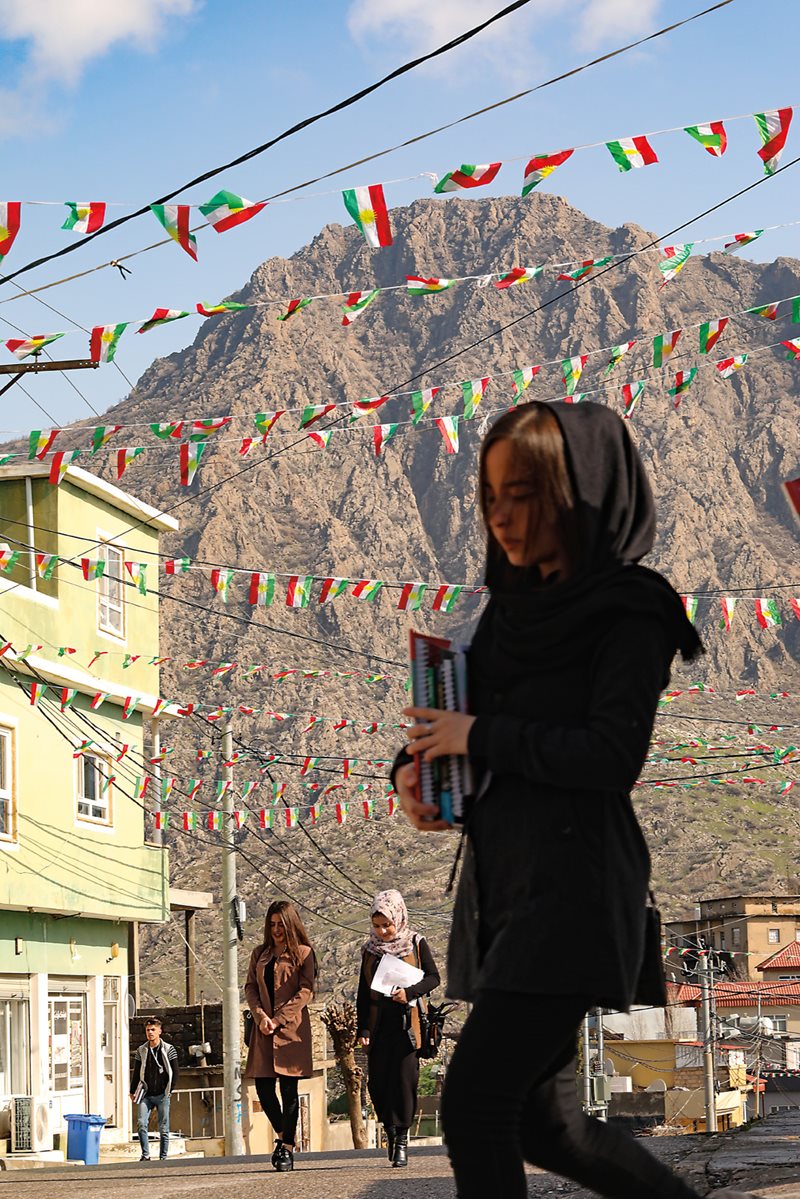 Mountains tower over students walking to school in Amedi. Space is at a premium in the one-square-kilometer city, making the preservation of historic sites a challenge in the face of ongoing development. 