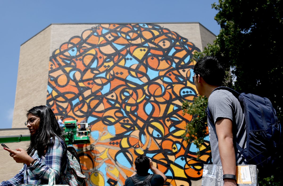 As students make their way across the University of Houston campus, “calligraffiti” artist eL Seed finishes his building-size mural on a wall of the Graduate College of Social Work. The mural is an Arabic translation of a quote from the city of Houston’s namesake, Sam Houston: “Knowledge is the food of genius, and my son, let no opportunity escape you to treasure up knowledge.”