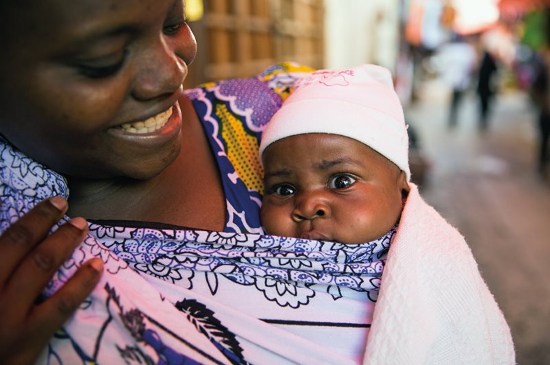 Kanga serve both as fashion and utility: A mother swaddles and carries her baby in her kanga, which allows her hands to stay free and her baby to stay close.