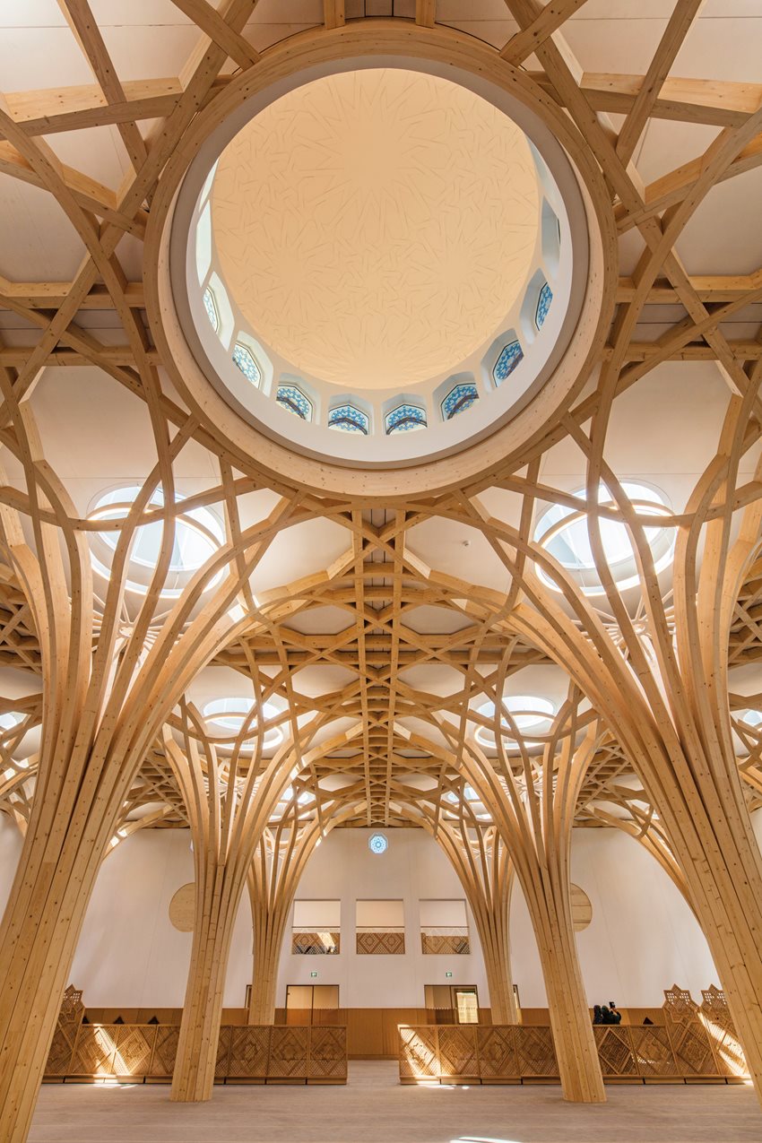 A forest of gracefully arced and interlaced columns creates the vaulting in the main prayer hall at the Central Mosque in Cambridge, England. Skylights above each column let in natural light during the day, and for summer cooling, louvered vents create natural convection. At night, energy-efficient led lighting takes over.