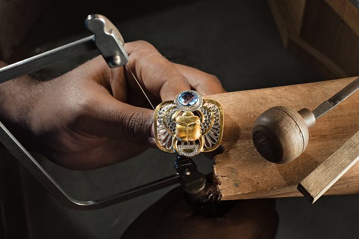 A craftsman puts the final touches on a scarab ring.